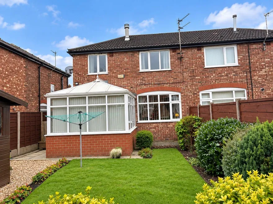 The rear of a red-brick semi-detached house with a conservatory, uPVC double glazing and a tiled roof.